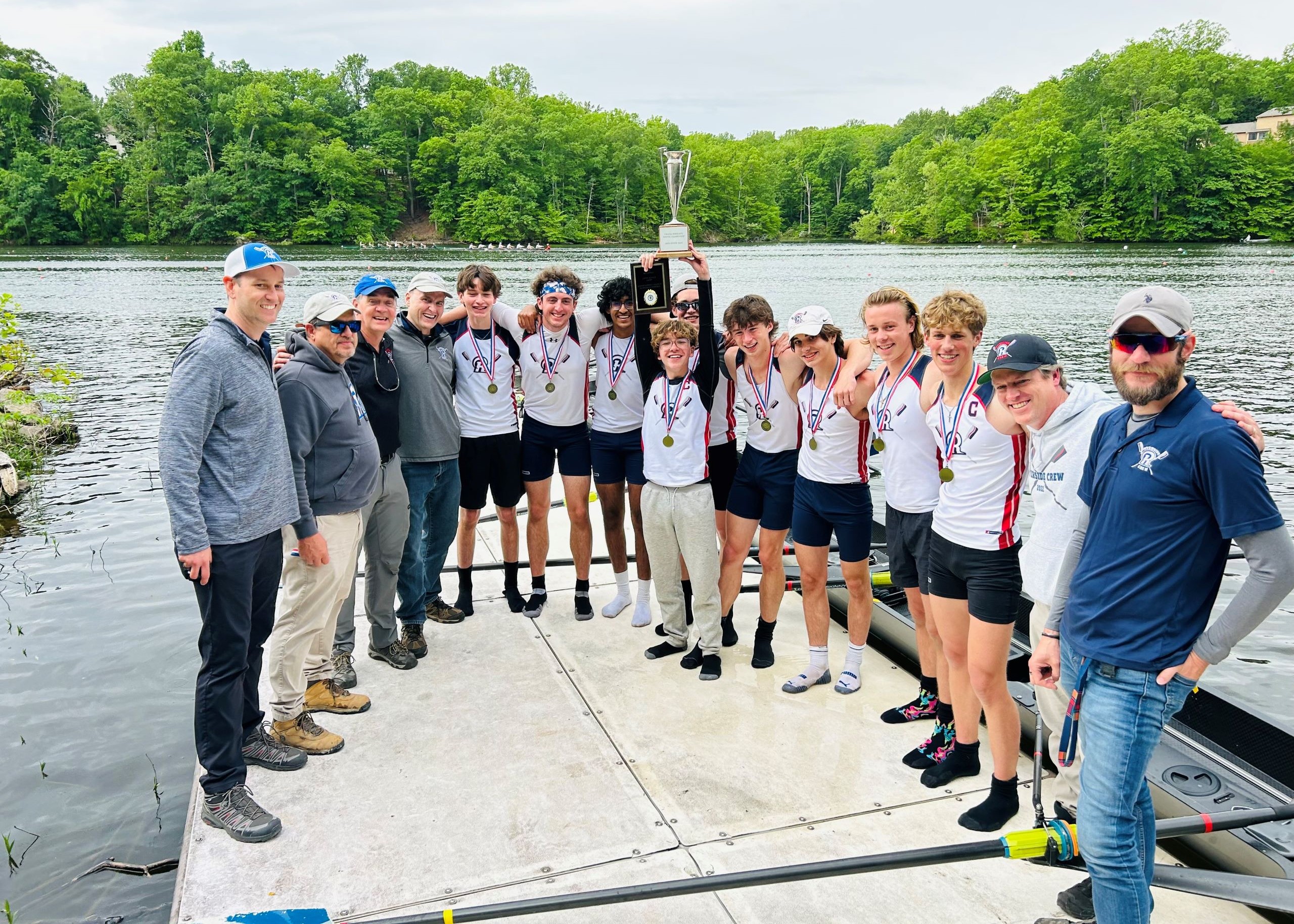 Riverside rowers and coaches celebrating together on the dock