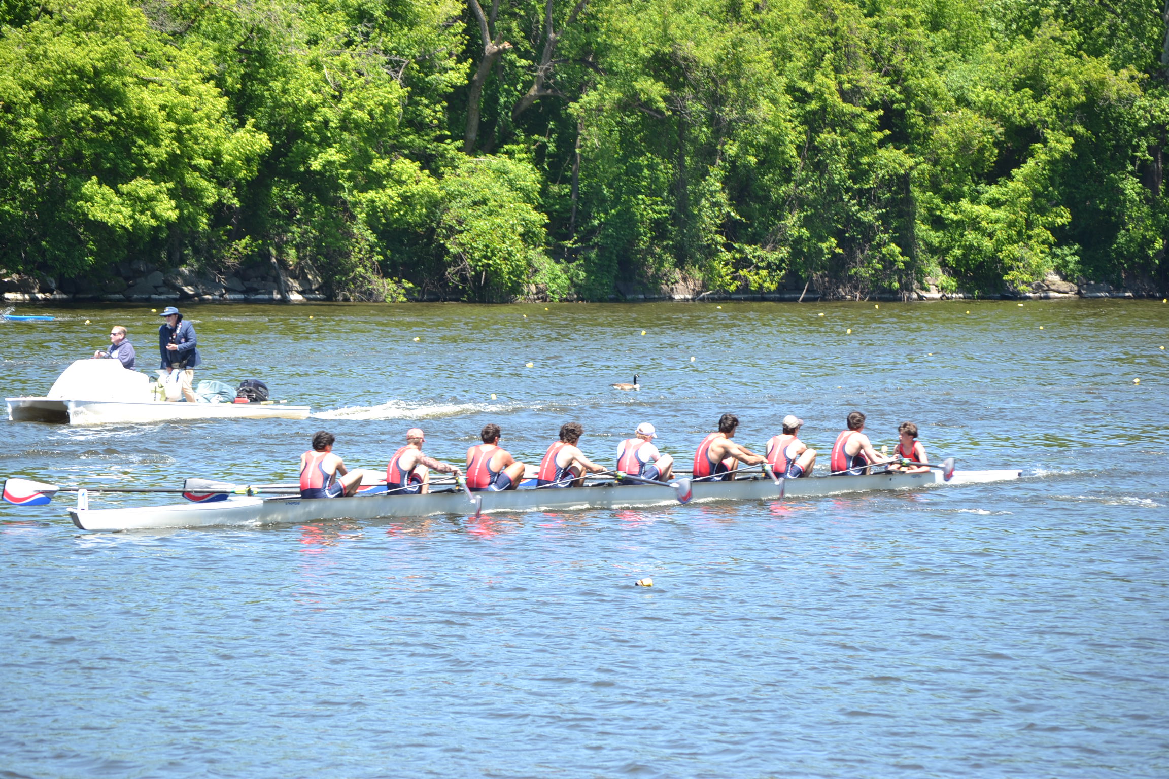 Riverside eight rowing together with a launch nearby