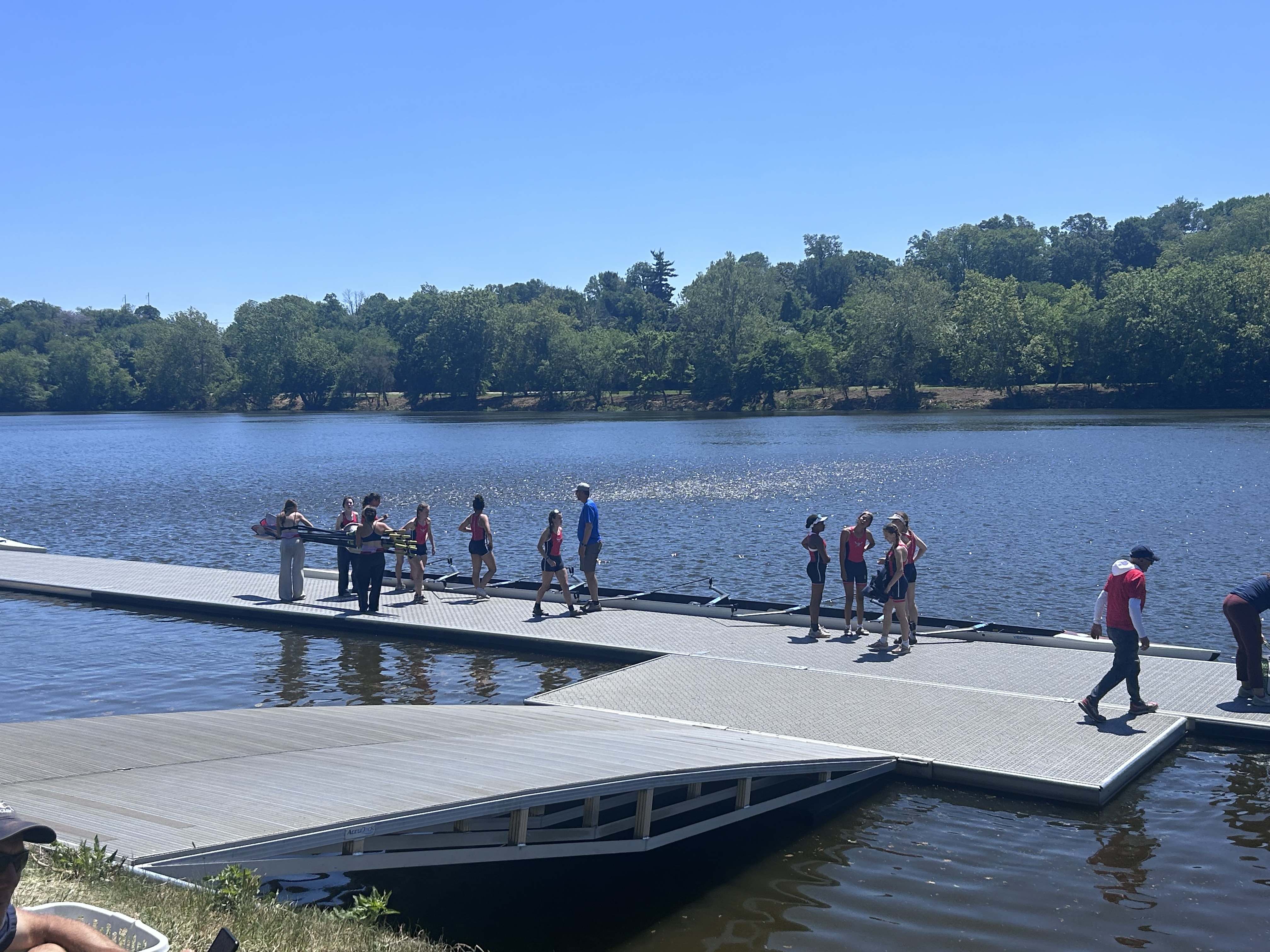 Athletes handling oars and rowing shells on the launch dock